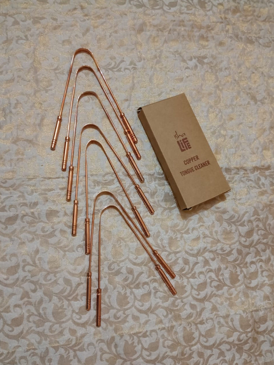 Set of copper brewing tools and a brown box on a textured beige surface