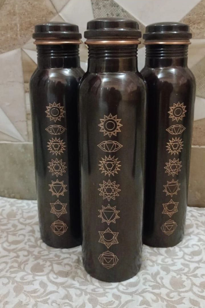Three black water bottles with gold designs on a tiled floor.